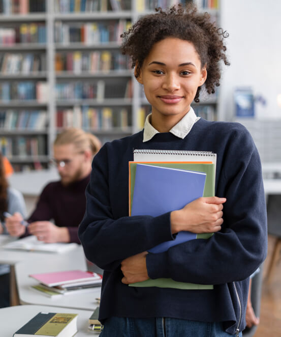 A smiling student holding her school books
