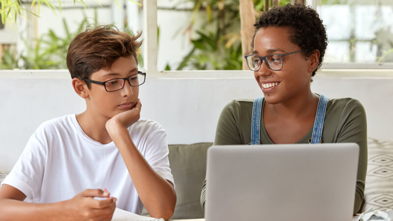 A teacher and a student smiling together over a laptop