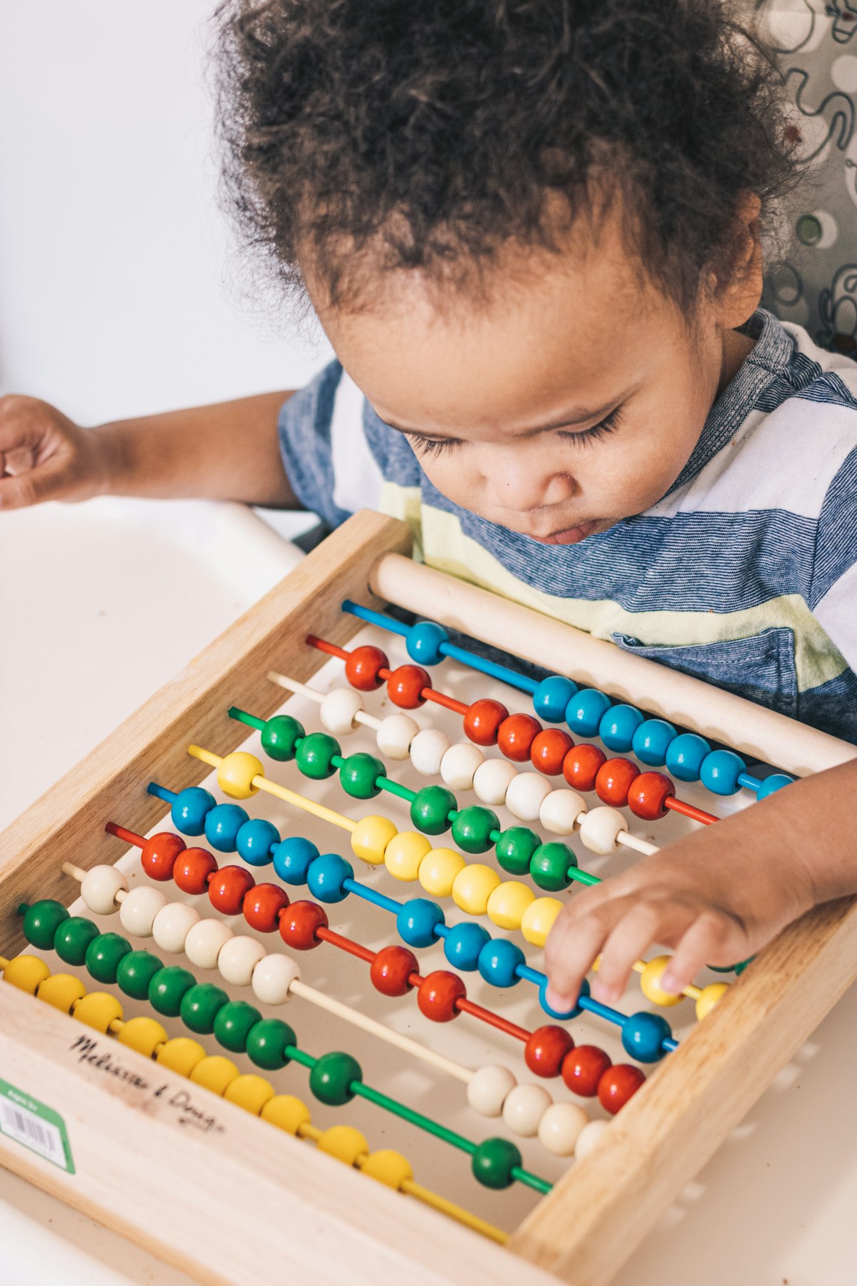 A young child counting beads on an abacus