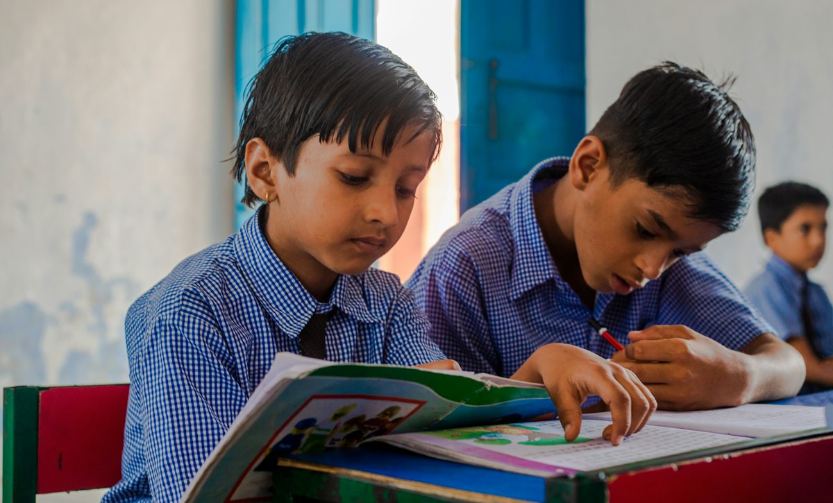 Two schoolboys studying together from a book
