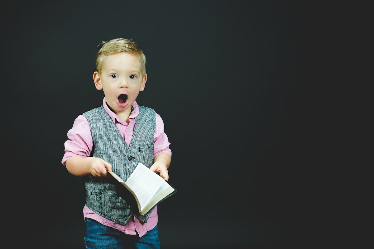 An expressive young boy holding a book