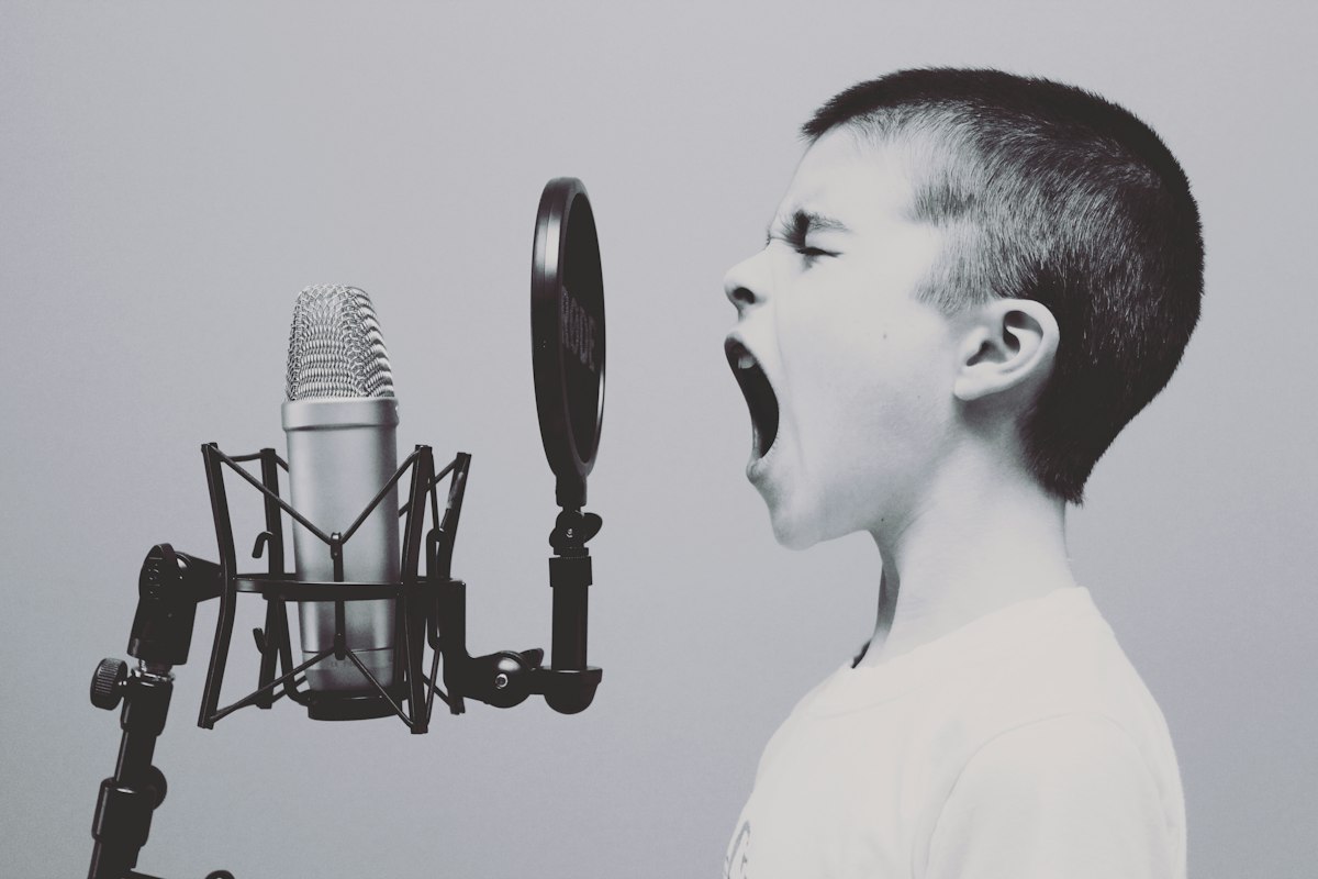 A boy speaking loudly into a studio microphone